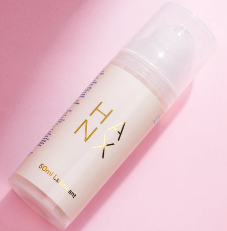 A 50ml bottle of HANX vegan lubricant with gold and white lettering against a pink background.